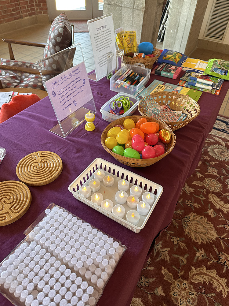 A table with a purple tablecloth and baskets of supplies to make a chalice out of a plastic Easter egg.