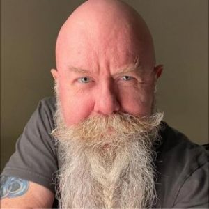white bald man with blue eyes and long grey beard smiles